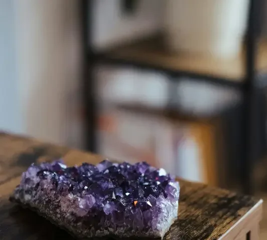 Mehrere Amethyst-Rohsteine als ruhiges Arrangement auf hellem Hintergrund; Produktfoto für Meditation und Achtsamkeit.