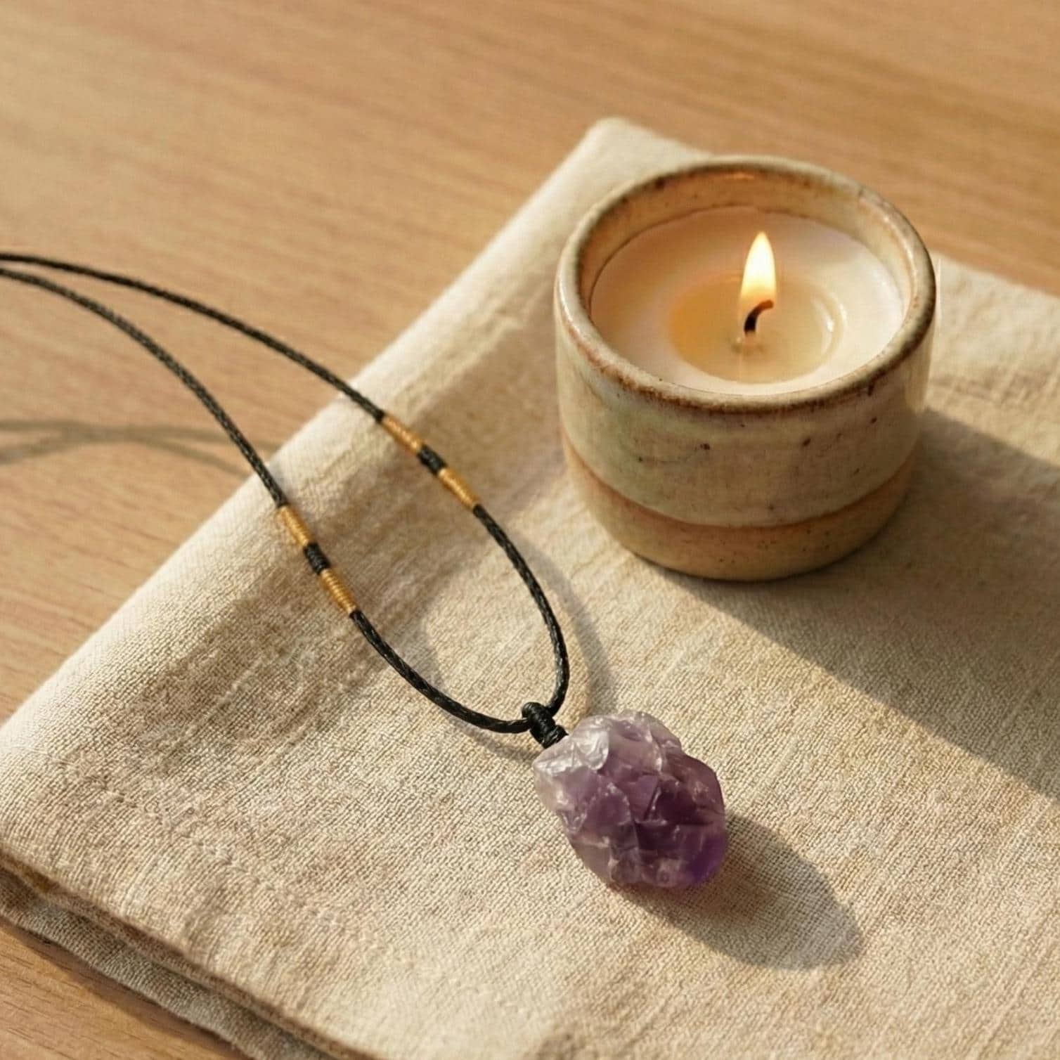 Rohstein Amethyst Anhänger auf einem Tisch mit brennender Kerze