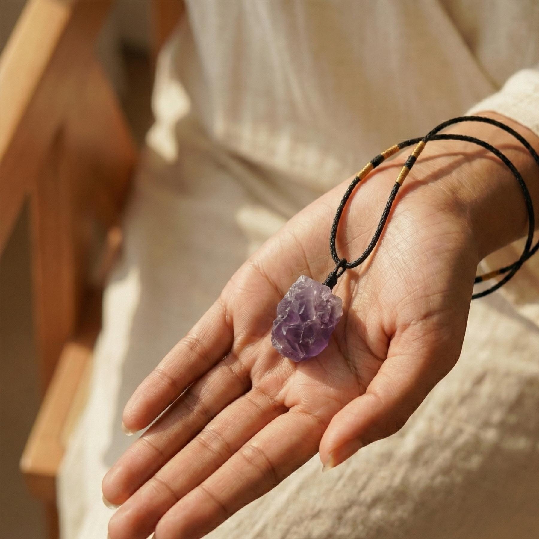 Rohstein Amethyst Anhänger in der Hand, symbolisiert spirituellen Schutz und Achtsamkeit.