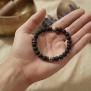 Hand mit Anti-Stress Armband aus Lava und Howlith für innere Ruhe.