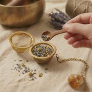 Detailaufnahme eines goldenen Teesiebs mit Citrin-Kristall und Kräutern
