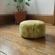 Gelbes Bio Meditationskissen in einer natürlichen Umgebung mit Pflanze