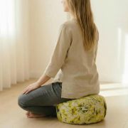 Frau sitzt auf grünem Bio Meditationskissen, ideal für Yoga und Meditation.