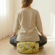 Person sitzt auf grünem Bio Meditationskissen mit Pflanzenfärbung, Rückenansicht.