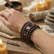 Holz Armband Set in erdigen Farben am Handgelenk, umgeben von Kerzen und Lavendel.