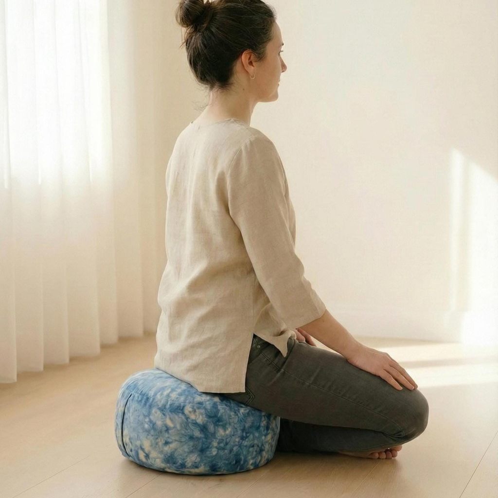 Seitliche Ansicht einer Frau beim Meditieren auf dem Vishuddha Chakra-Kissen – ergonomischer Sitz, entlastet Rücken und Nacken sanft.