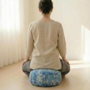 Frau meditiert in aufrechter Haltung auf dem blauen Vishuddha Meditationskissen – unterstützt Kehlchakra, freie Atmung und ruhige Präsenz.