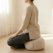 Seitliche Ansicht einer meditierenden Frau auf dem weißen Kissen – unterstützt eine aufrechte, bequeme Haltung für Zazen, Pranayama & Achtsamkeit.