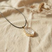 Klarer Quarz Rohstein Anhänger auf hellem Stoff präsentiert seine natürliche Schönheit.