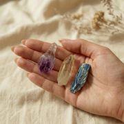 Berührung der Rohsteine Amethyst, Bergkristall und Blaukyanit in der Hand – für Fokus und energetische Verbindung.