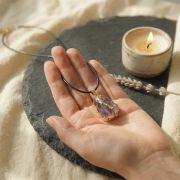 Lila Amethyst mit goldener Einfassung auf hellem Leinenhintergrund