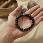 Unisex Perlenarmband mit grünem Stein getragen am Handgelenk in meditativer Pose.