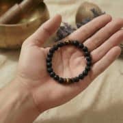 Das Armband liegt auf einem natürlichen Holzuntergrund, um die organischen Materialien zu betonen.