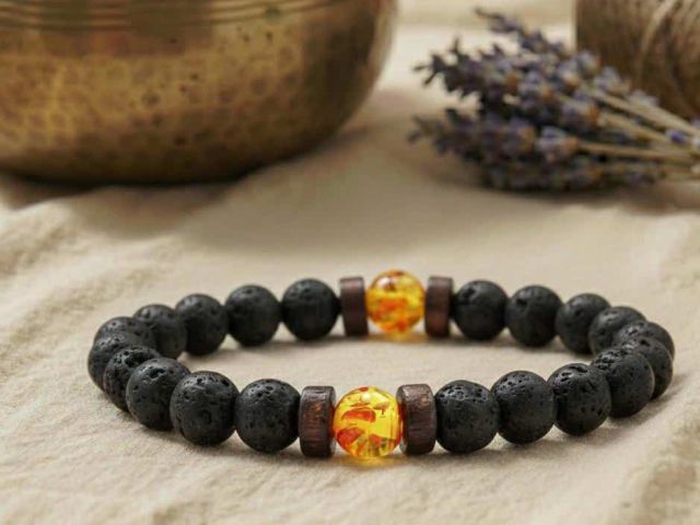 Nahaufnahme des schwarzen Lava-Armbands mit zwei honiggelben, leicht transparenten Calcit-Perlen.