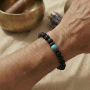 Ein Mann trägt das schwarze Lavaperlen-Armband dezent zu einer Armbanduhr.