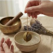 Arrangement aus goldenem Teesieb, Amethyst, getrocknetem Lavendel und einer tibetischen Klangschale im Hintergrund.