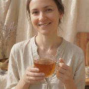 Das goldene Citrin Tee-Ei liegt neben einer Dose mit gelbem Bio-Tee, einem kleinen Honiglöffel und einem Wellness-Tagebuch auf einem hellen Tisch.