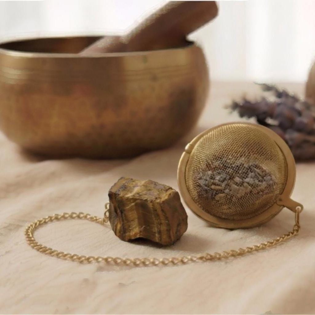 Goldenes Tee-Ei und Amethyst auf Leinen, umgeben von einer Klangschale.