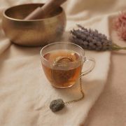Labradorit Teesieb in einer Teetasse mit dampfendem Tee und Lavendel im Hintergrund.