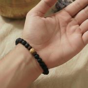 Lava Armband mit Bildstein auf einem Handgelenk, erdige Farben und Naturstein-Perlen.
