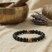 Lava Armband mit Bildstein und Naturstein Perlen auf einem Tisch mit einer Schale im Hintergrund.