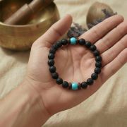 Lava Armband mit Türkis in der Hand gehalten, ideal für Erdung und Stil.