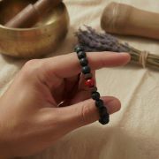 Detailaufnahme eines Lava Armbands mit rotem Jaspis in einer Hand, ideal für Yoga und Erdung.