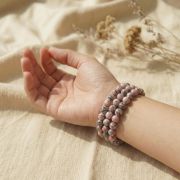 Detailaufnahme eines Rosa Zebra Jaspis Armbands an einer Hand auf hellem Hintergrund.