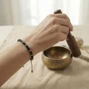 Schwarzer Jaspis Armband aus Flachperlen an einer Hand, die eine Schaalenglocke hält.