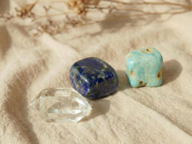 Nahaufnahme der Wassersteine Lapislazuli, Aragonit und Quarz auf einem Stoffuntergrund.