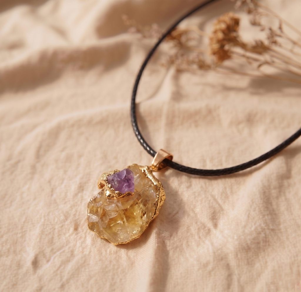 Detaillierte Nahaufnahme des rohen Citrin Kettenanhängers mit Amethyst und Textilband auf hellem Leinenstoff.