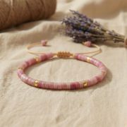 Detailaufnahme eines Rhodonit Armbands mit rosa Natursteinperlen und goldenen Akzenten.