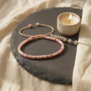 Rhodonit Armband mit goldenen Akzenten auf schwarzem Untergrund, ideal für Herzchakra.