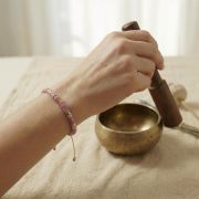 Rhodonit Armband mit goldenen Akzenten am Handgelenk während der Meditation.