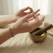 Hände in Meditationshaltung mit Rhodonit Armband und Klangschale