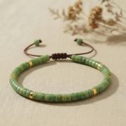 Serpentin Armband mit grünen Flachperlen und braunem Verschluss, minimalistisch und elegant.