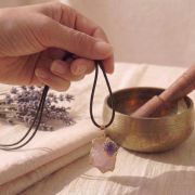 Hand hält eine Rosenquarz und Amethyst Goldkette mit Lederband.